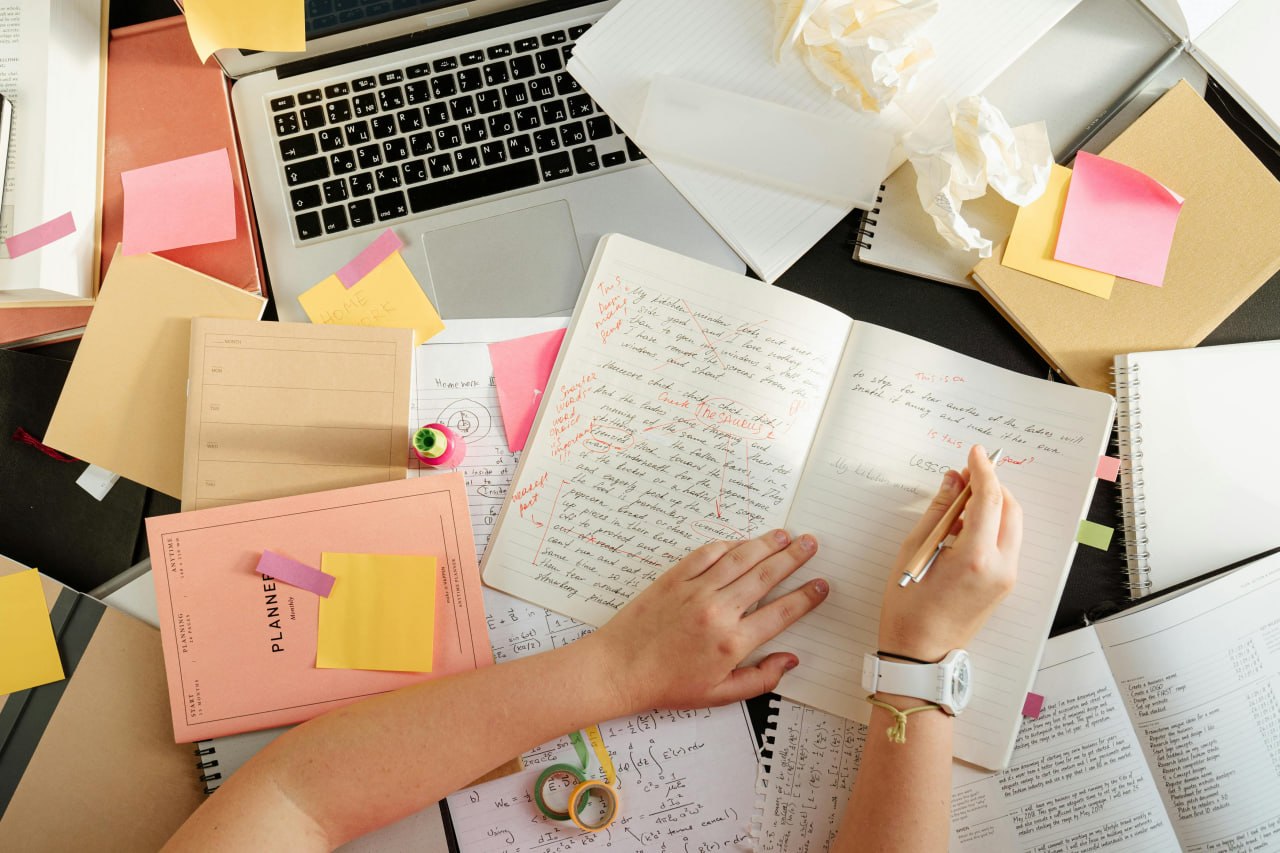 A busy desk covered in journals, planners, and notes — tracking everything leads to burnout